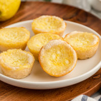 Lemon Chess Tartlets on a white plate on top of a wooden serving board