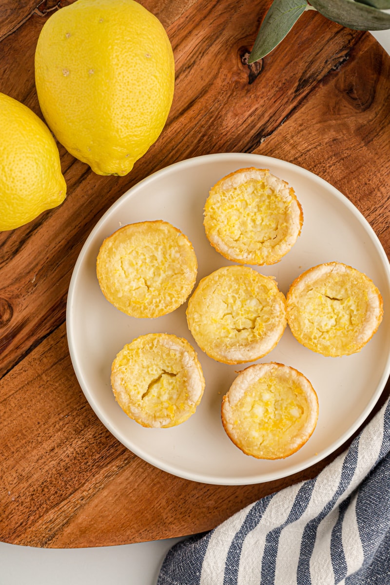 overhead view of Lemon Chess Tartlets on a white plate on a wooden surface