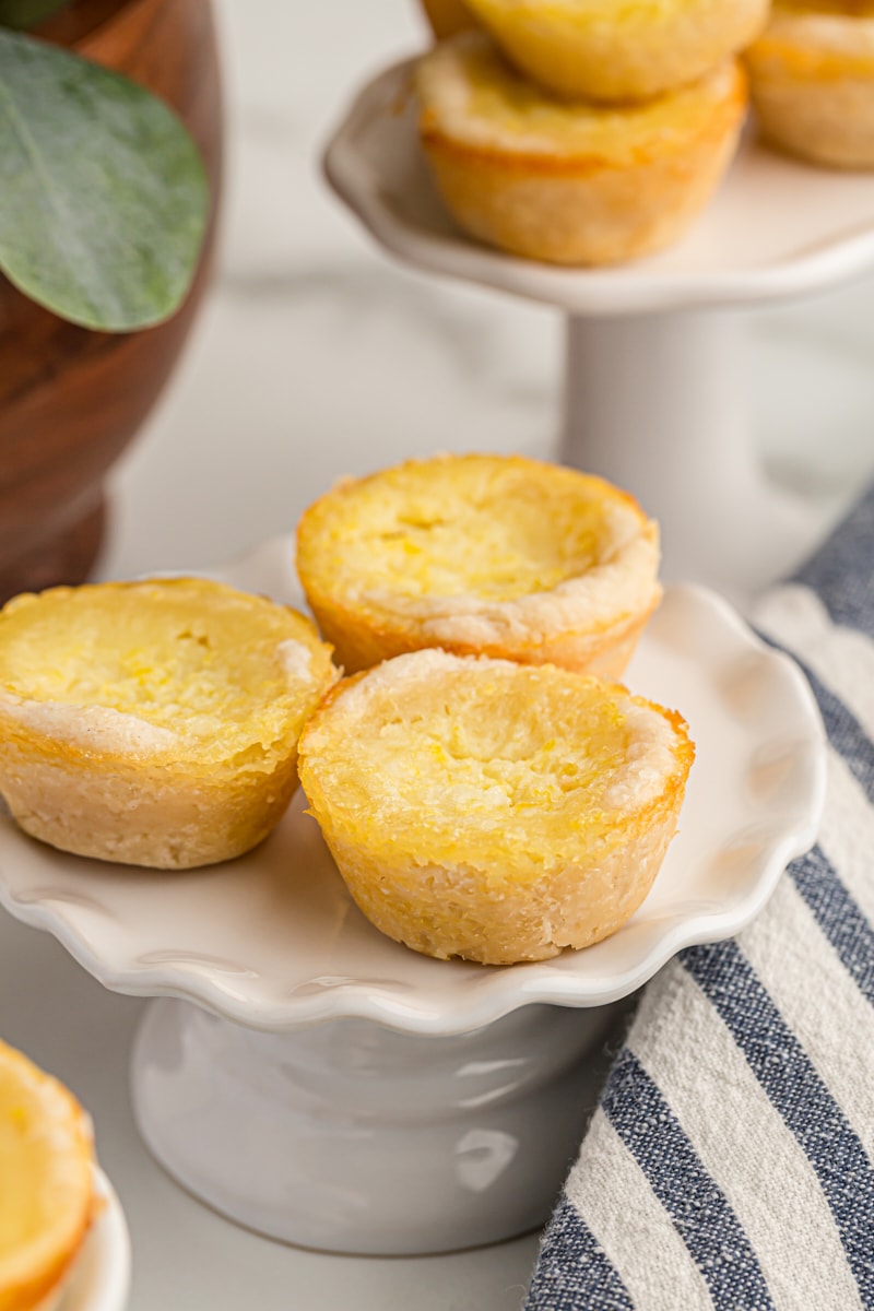 three Lemon Chess Tartlets on a small white pedestal