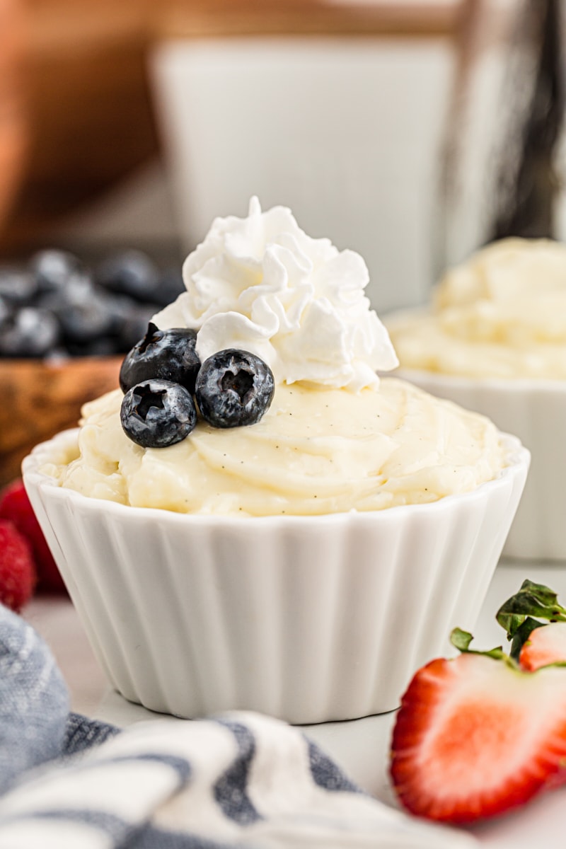 Cup of homemade vanilla pudding topped with whipped cream and blueberries