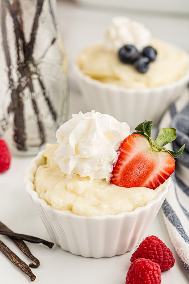 This homemade vanilla pudding is richer and creamier than anything from a box! Serve it as-is, with toppings, or use it in more desserts. Two cups of vanilla pudding topped with whipped cream and berries