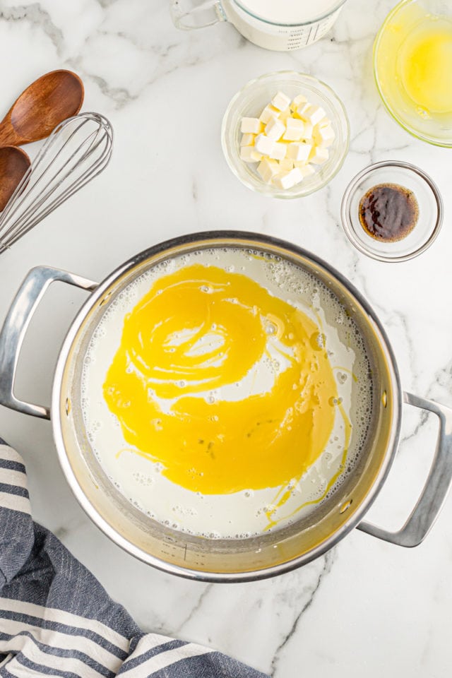 Overhead view of egg yolks added to pudding mixture in saucepan