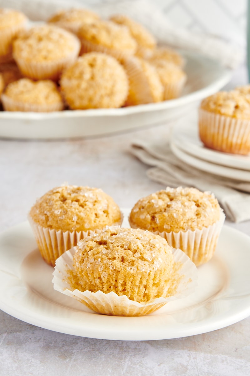 3 cinnamon mini muffins on white plate, with wrapper pulled from sides of center muffin