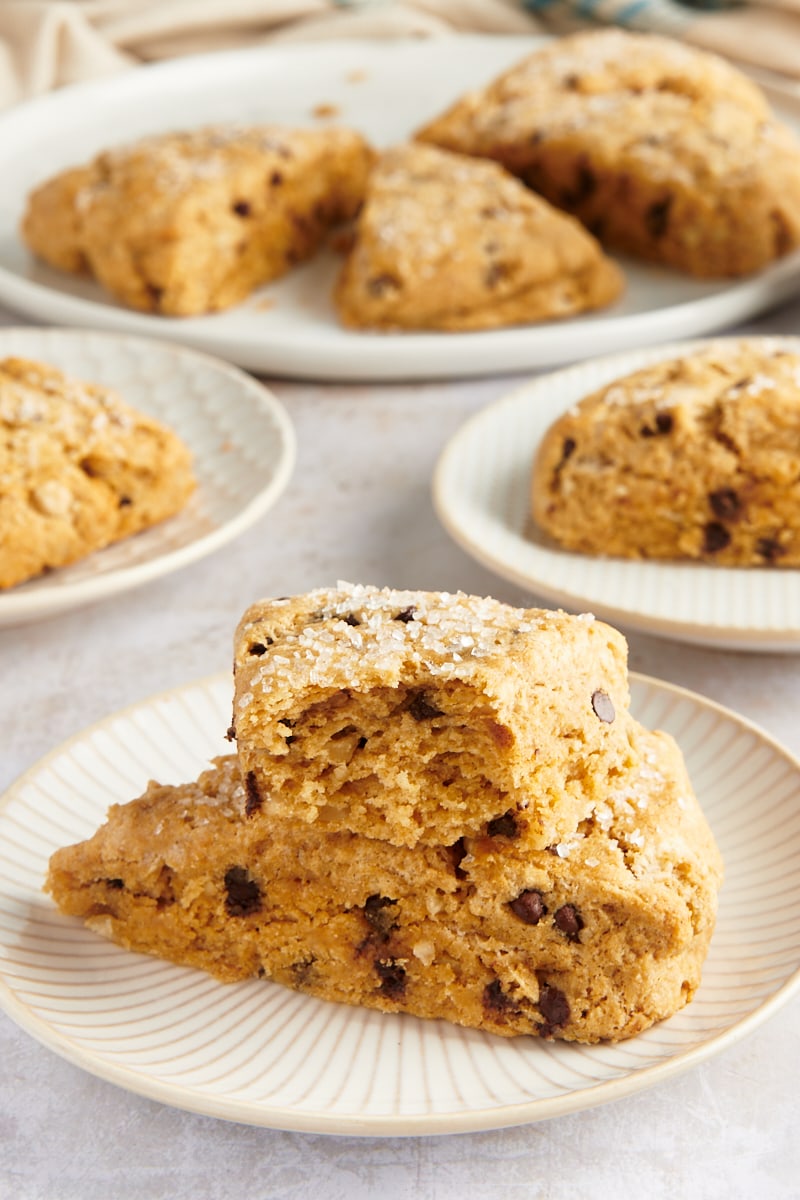 Stack of 2 chocolate chip-hazelnut scones on plate, with additional scones in background