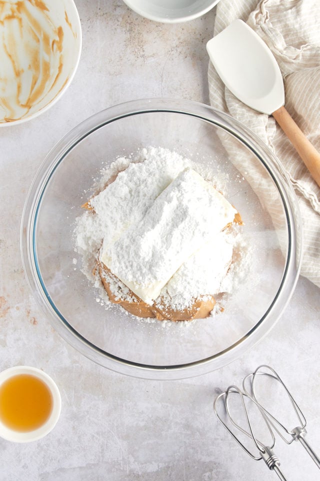 overhead view of cream cheese, peanut butter, and confectioners' sugar in a glass mixing bowl