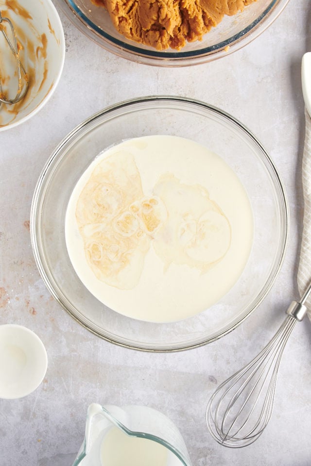 overhead view of heavy cream and vanilla extract in a glass mixing bowl