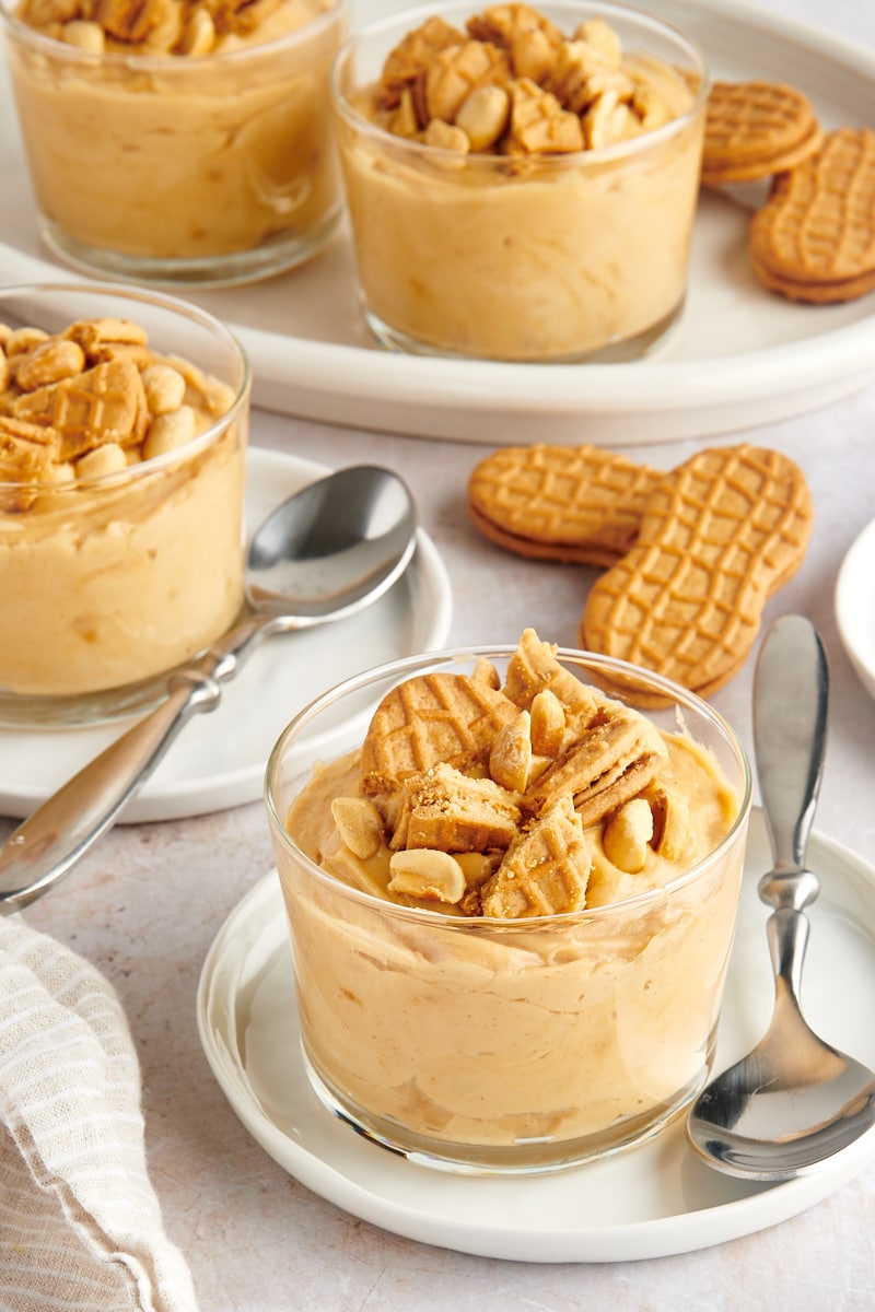 servings of Peanut Butter Mousse in clear glasses topped with peanuts and cookie pieces