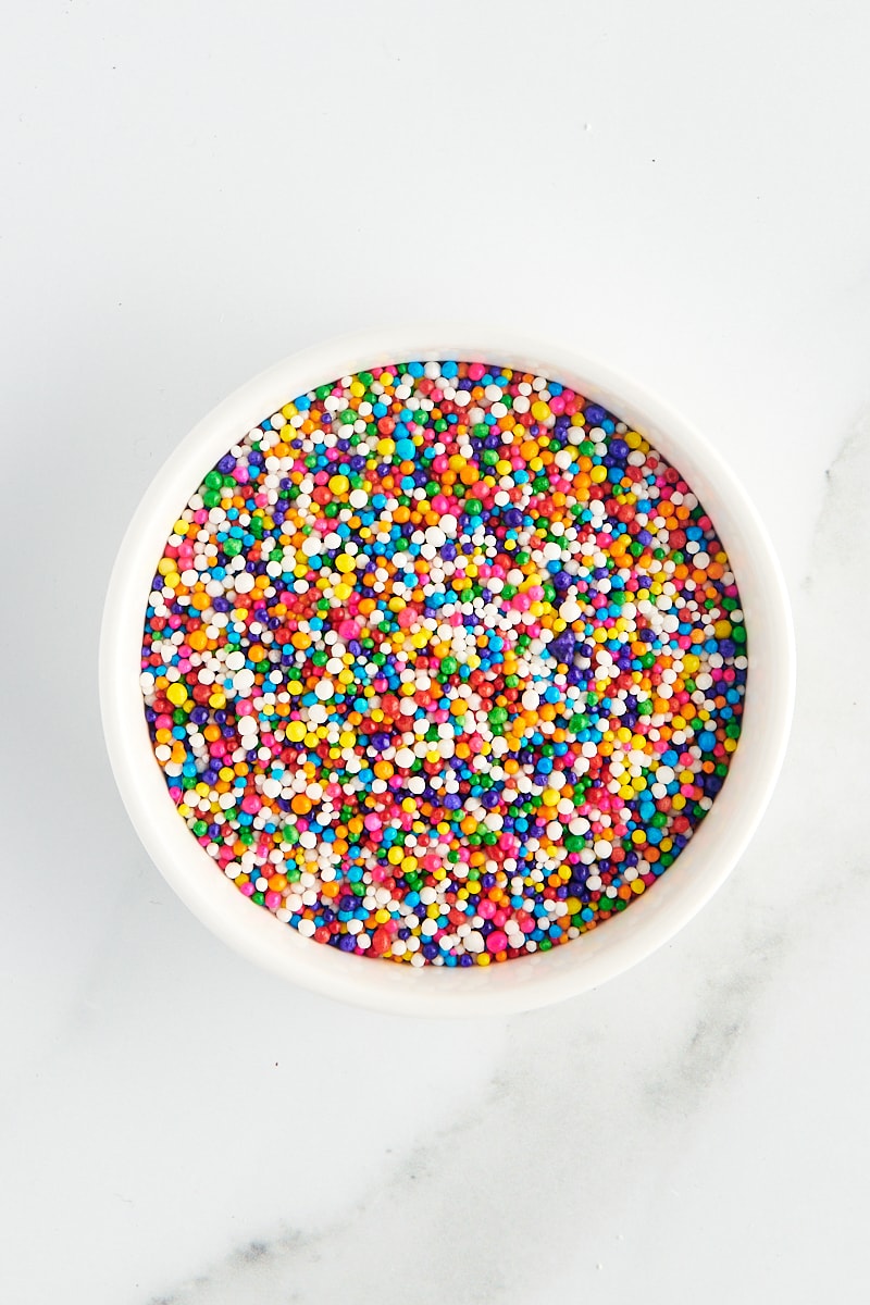 overhead view of nonpareils in a white bowl on a marble surface