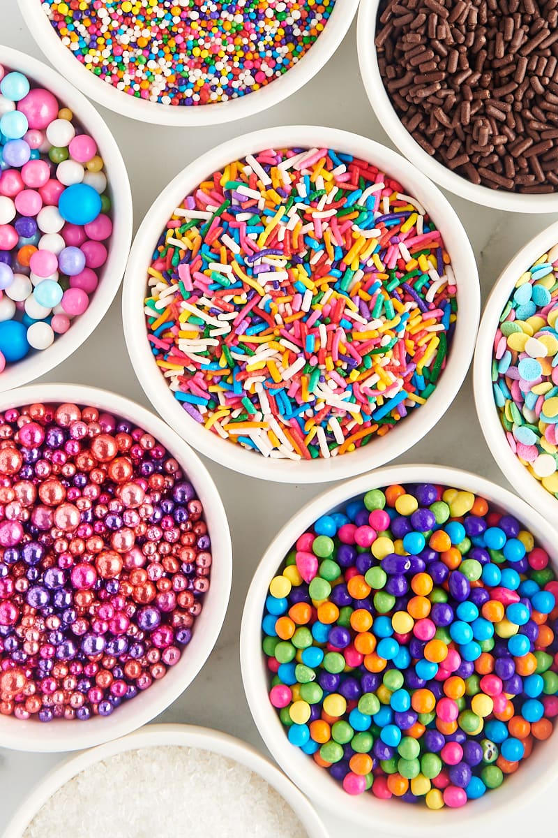 overhead view of a variety of sprinkles in white bowls