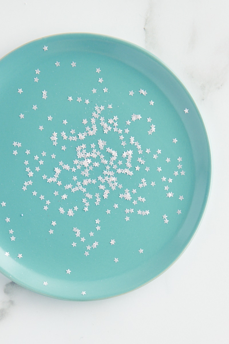 overhead view of star-shaped edible glitter on a turquoise plate