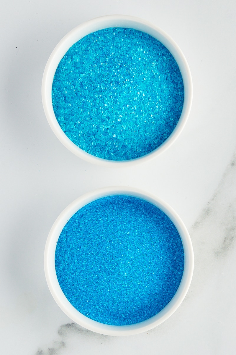 overhead view of blue sparkling sugar and sanding sugar in white bowls