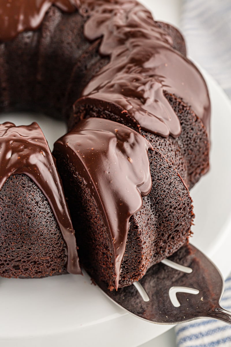 Removing a slice of chocolate sour cream Bundt cake from cake stand