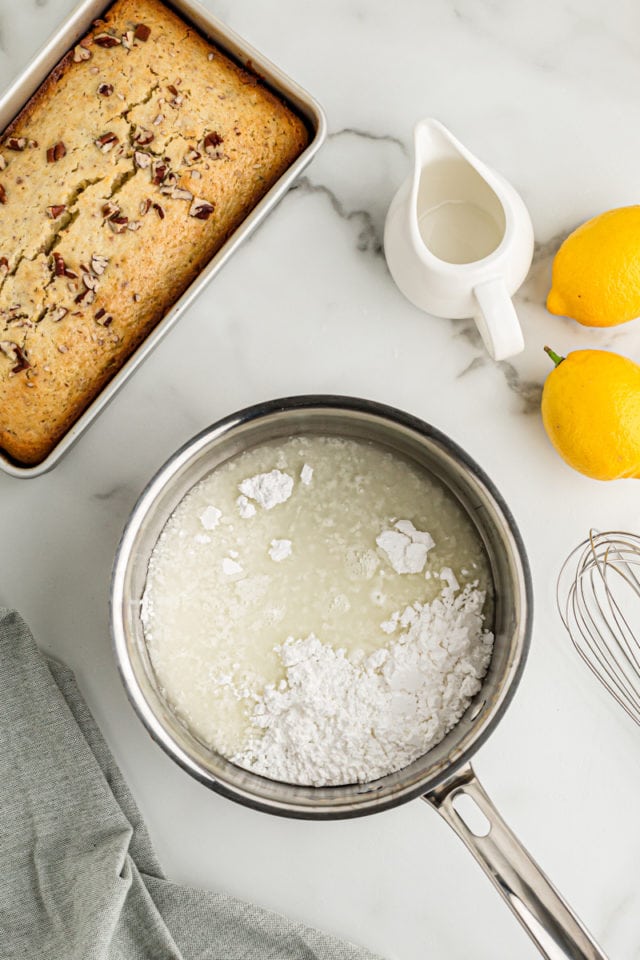 Overhead view of lemon bread in pan and glaze ingredients in saucepan