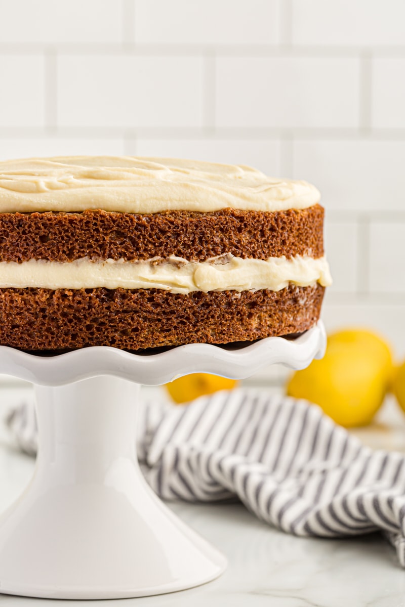 Whole lemon cream cake on cake stand, viewed from side to show layers