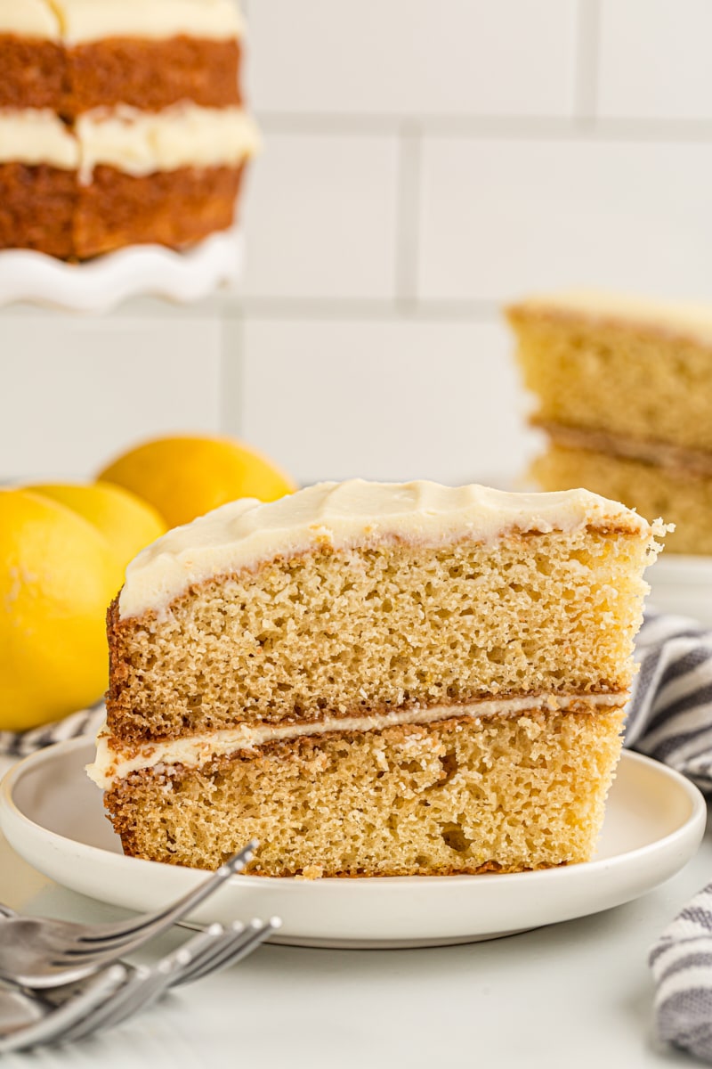 Side view of lemon cream cake on plate, with remaining cake in background