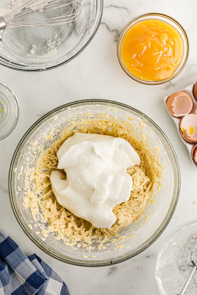 Overhead view of egg whites added to bowl of cake batter