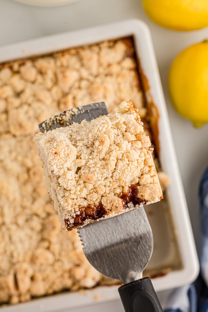 Spatula holding piece of lemon yogurt crumb cake over pan