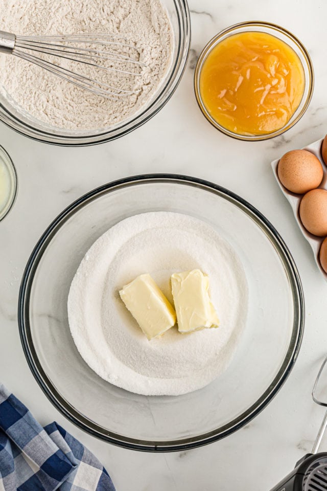 Overhead view of butter and sugar in glass mixing bowl