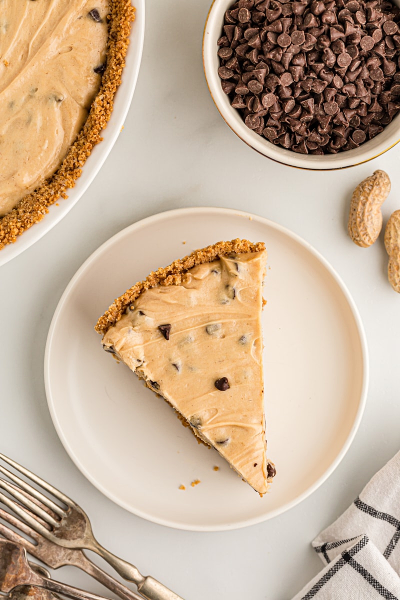 Overhead view of peanut butter chocolate chip pie on plate with rest of pie and chocolate chips in background