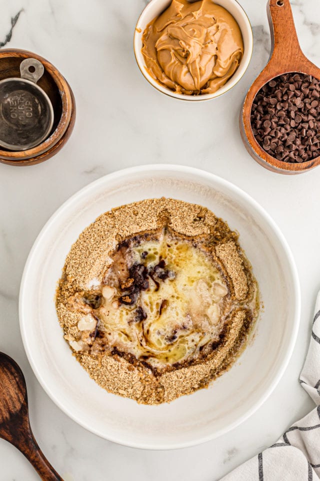 Overhead view of ingredients for graham cracker crust in mixing bowl