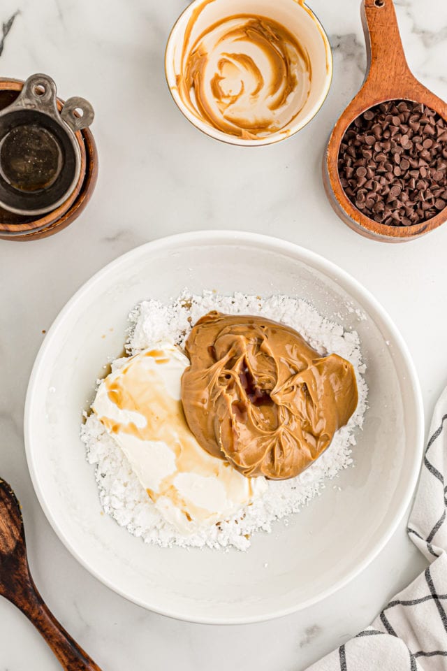 Overhead view of peanut butter, vanilla, cream cheese, and sugar in mixing bowl