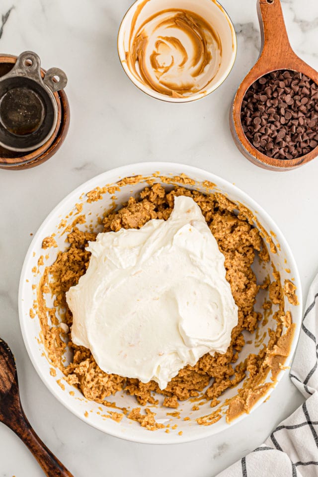 Overhead view of whipped cream added to bowl of peanut butter filling