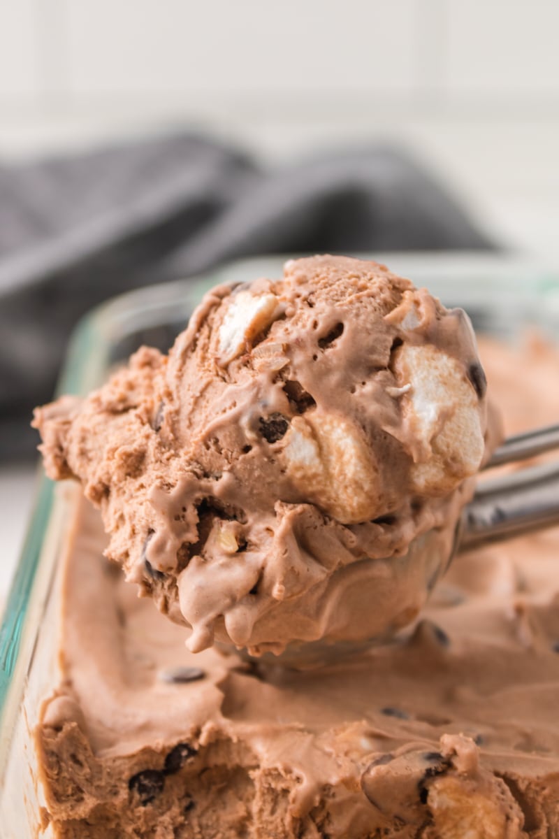 an ice cream scoop filled with rocky road ice cream sitting on top of more ice cream in a glass pan