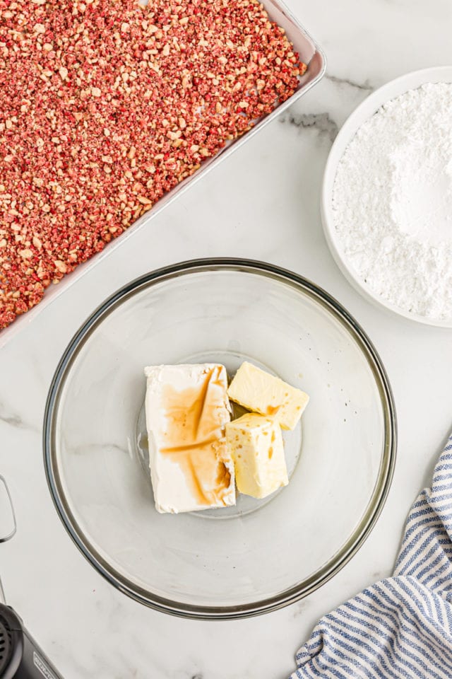 Overhead view of butter, cream cheese, and vanilla in glass mixing bowl