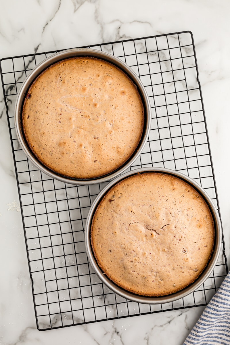 Overhead view of two strawberry crunch cake layers in baking pans on wire rack