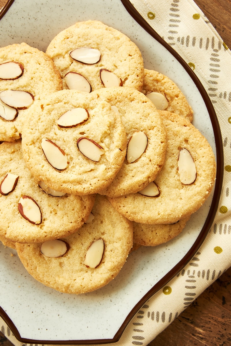 overhead view of almond cookies piled on a brown speckled plate