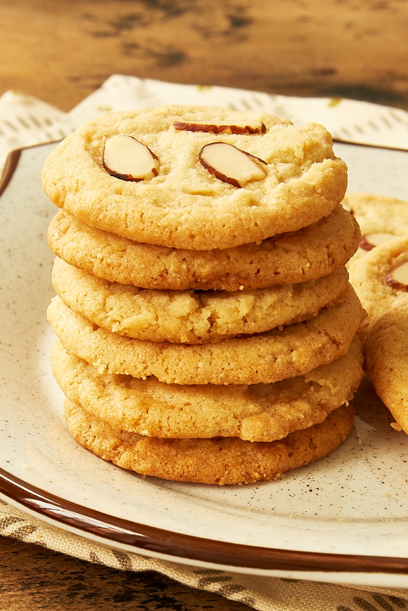 stack of almond cookies on a brown speckled white plate