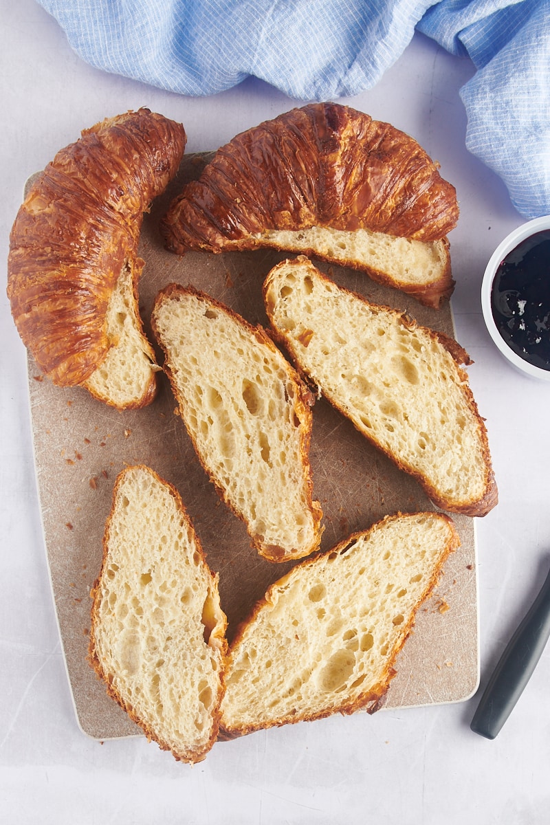 Overhead view of halved croissants on cutting board