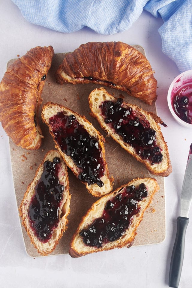 Overhead view of jam spread onto the bottoms of croissants