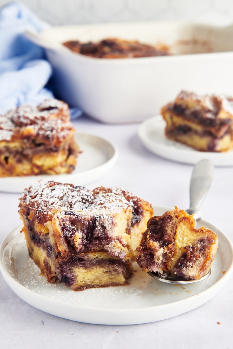 Three plates of blueberry croissant bread pudding, with baking dish in background