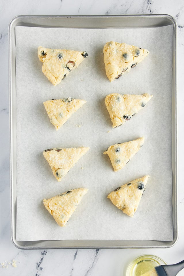 a baking sheet with blueberry scones brushed with egg white and sprinkled with coarse sugar before going into the oven