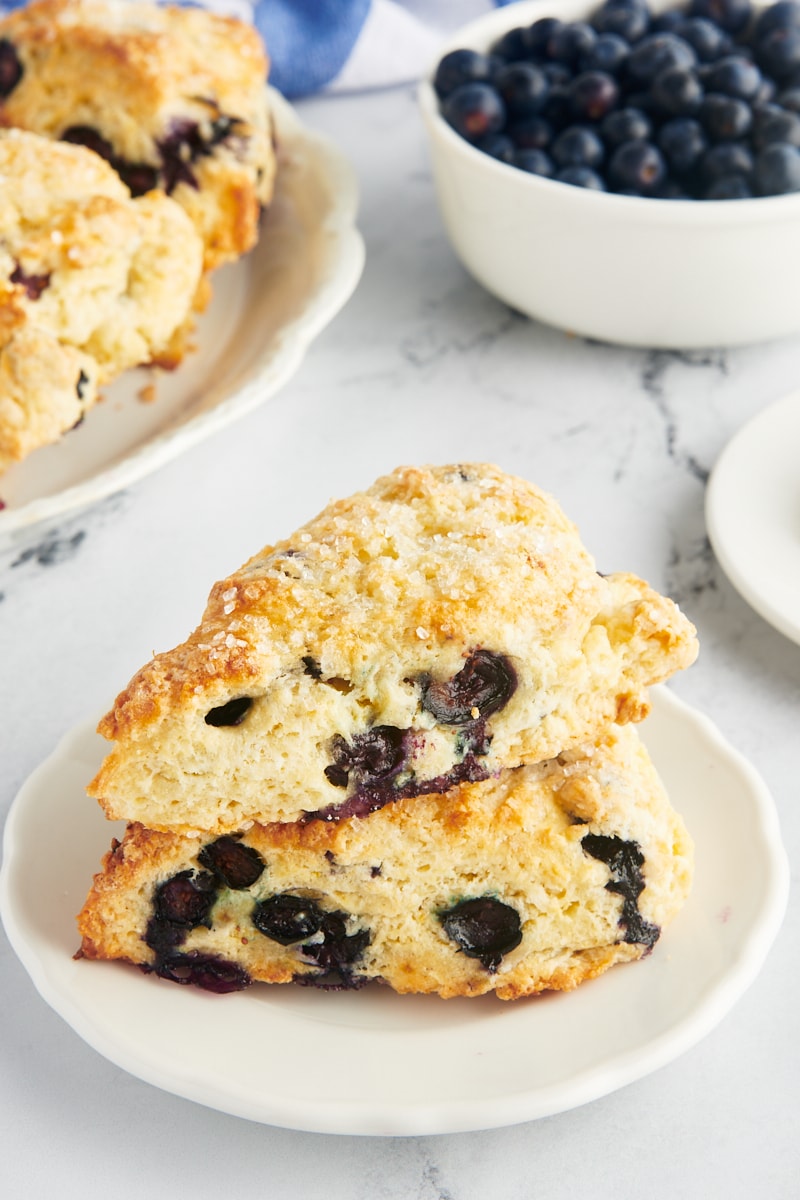 two blueberry scones stacked on a white plate