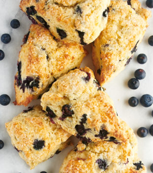overhead view of blueberry scones and blueberries on a white surface