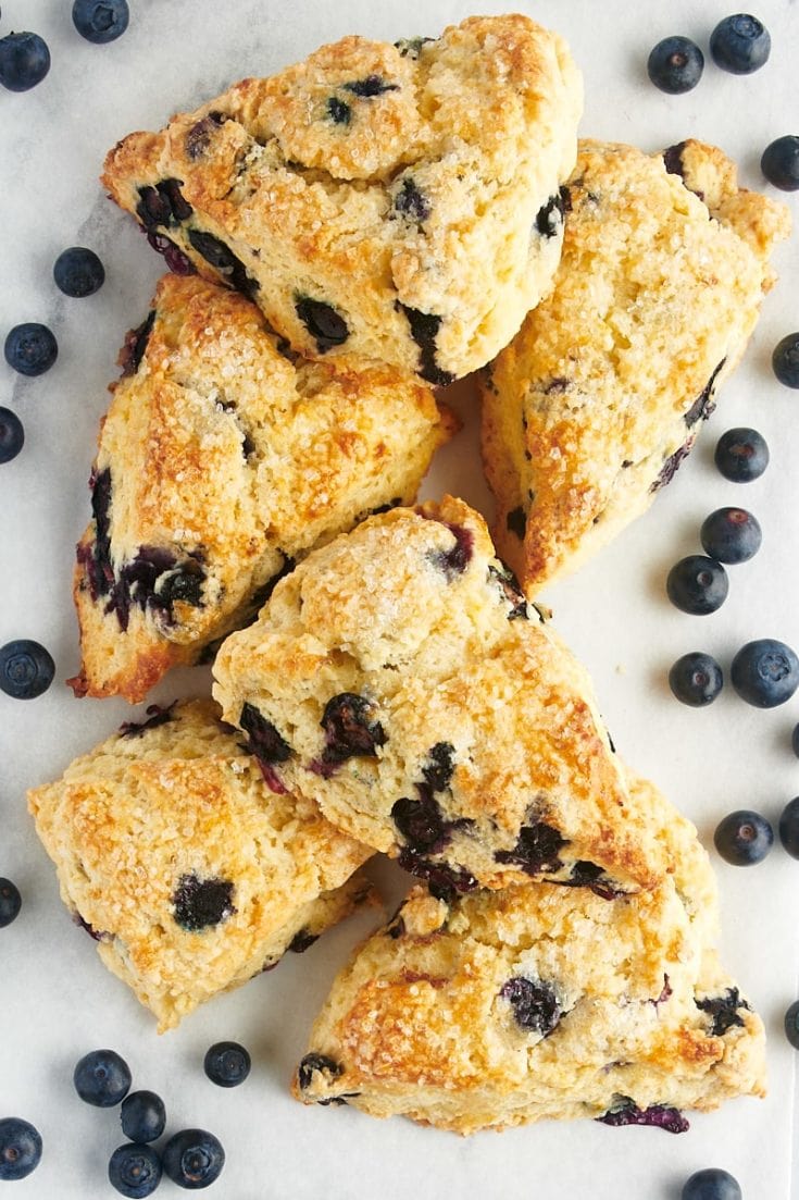 overhead view of blueberry scones and blueberries on a white surface