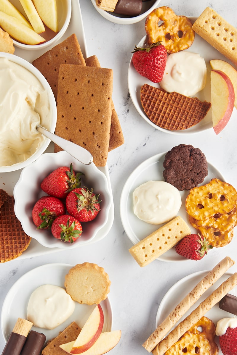 Overhead view of dessert board and plates with cheesecake dip and dippers