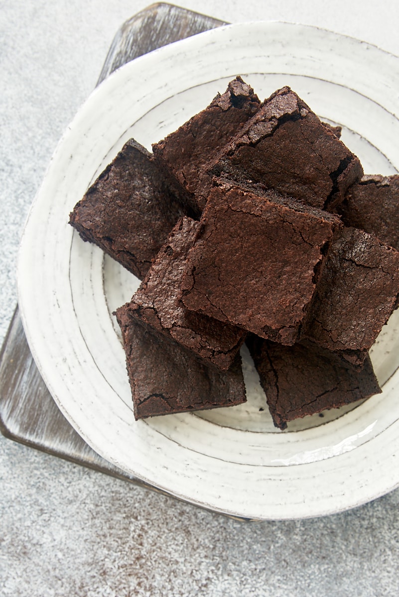overhead view of cocoa powder brownies piled on a white plate