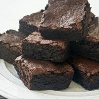 dark cocoa powder brownies piled on a white plate