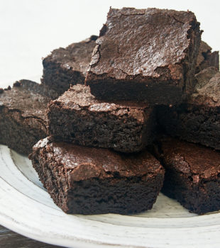 dark cocoa powder brownies piled on a white plate