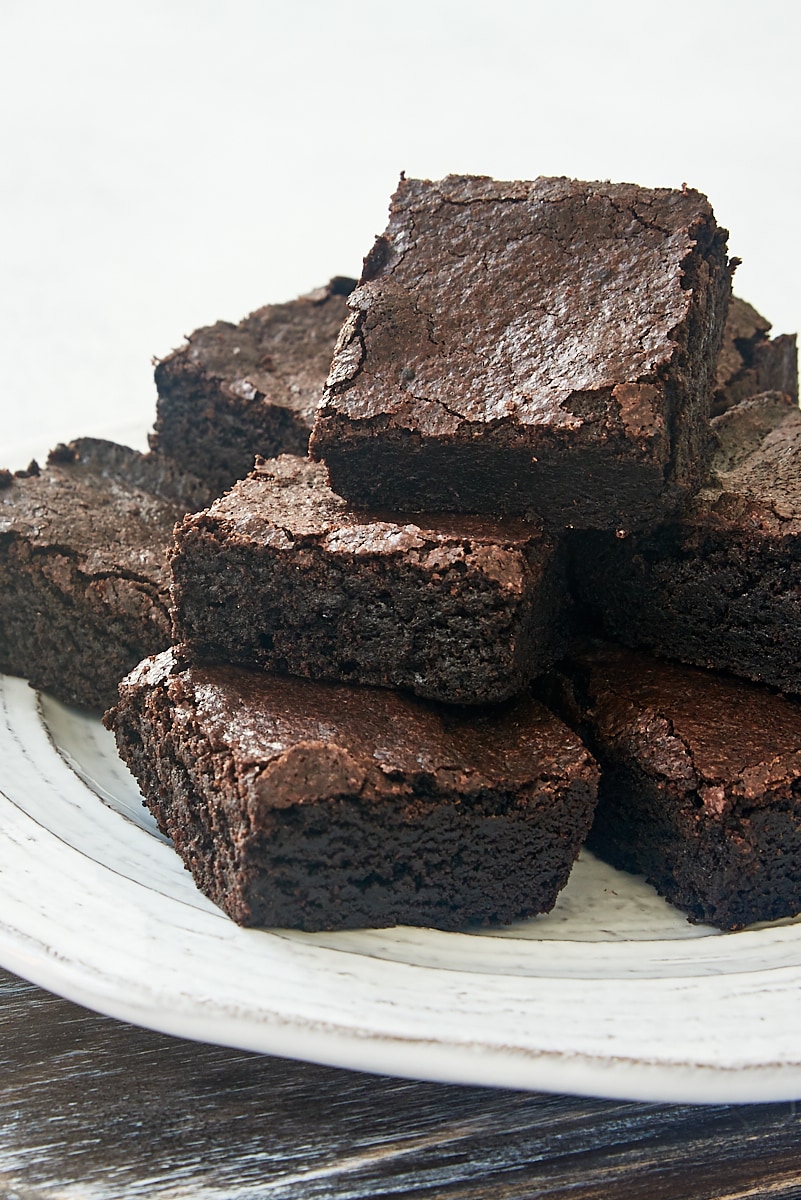 dark cocoa powder brownies piled on a white plate