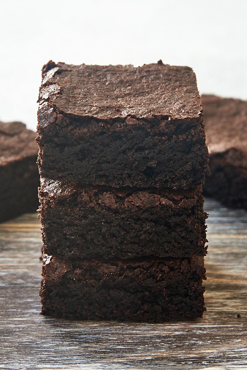 three cocoa powder brownies stacked on a wooden surface