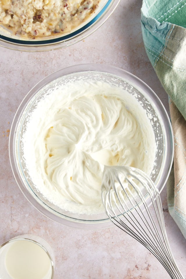 Overhead view of whipped cream in glass bowl with whisk