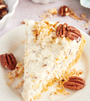 Slice of millionaire pie on plate with toasted coconut and pecans for garnish