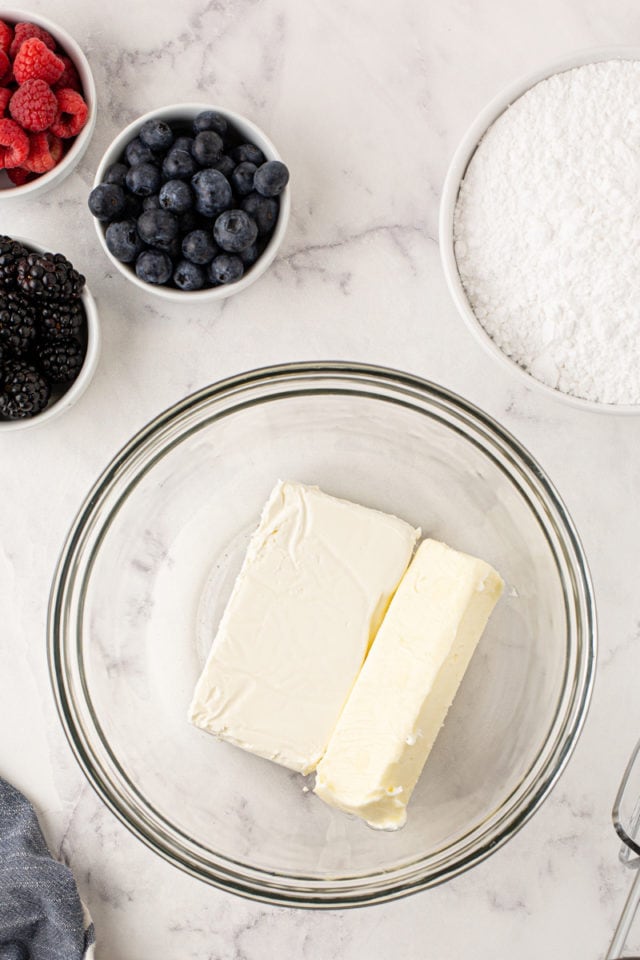 overhead view of butter and cream cheese in a glass mixing bowl