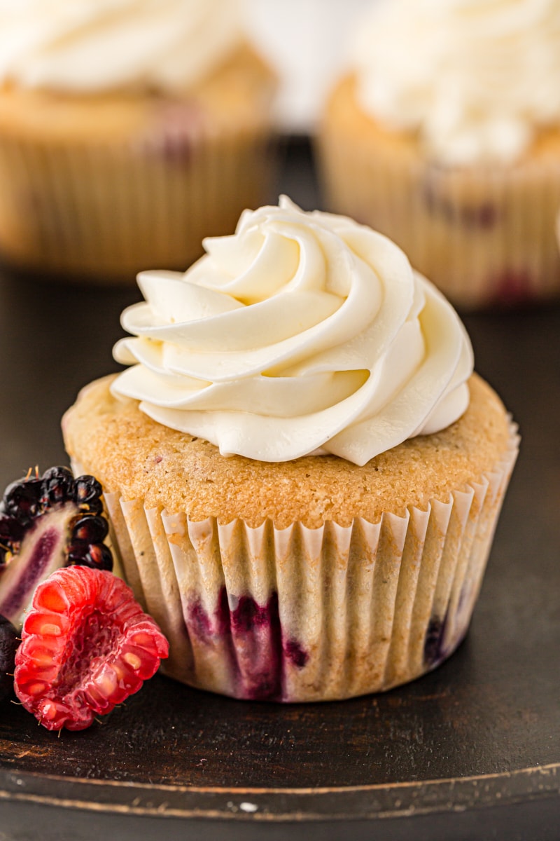 a berry cupcake topped with cream cheese frosting