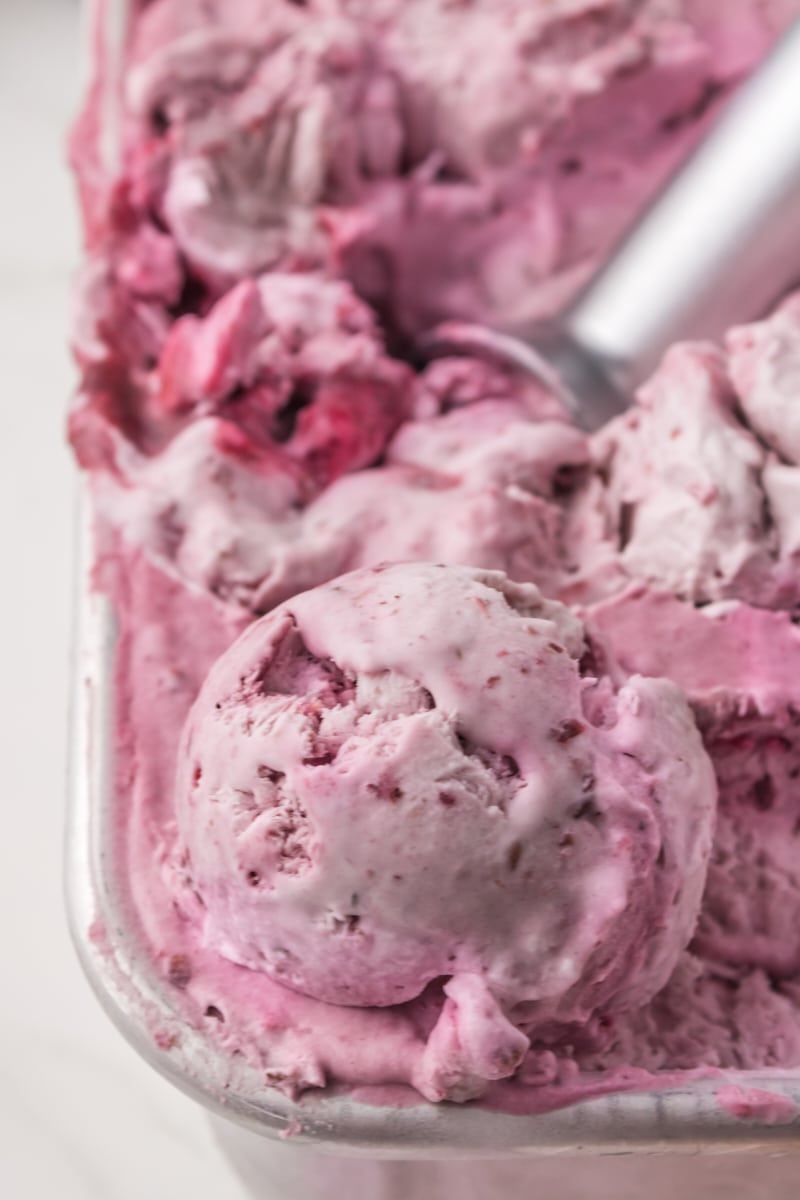 a container of blackberry ice cream with a scoop of the ice cream on top