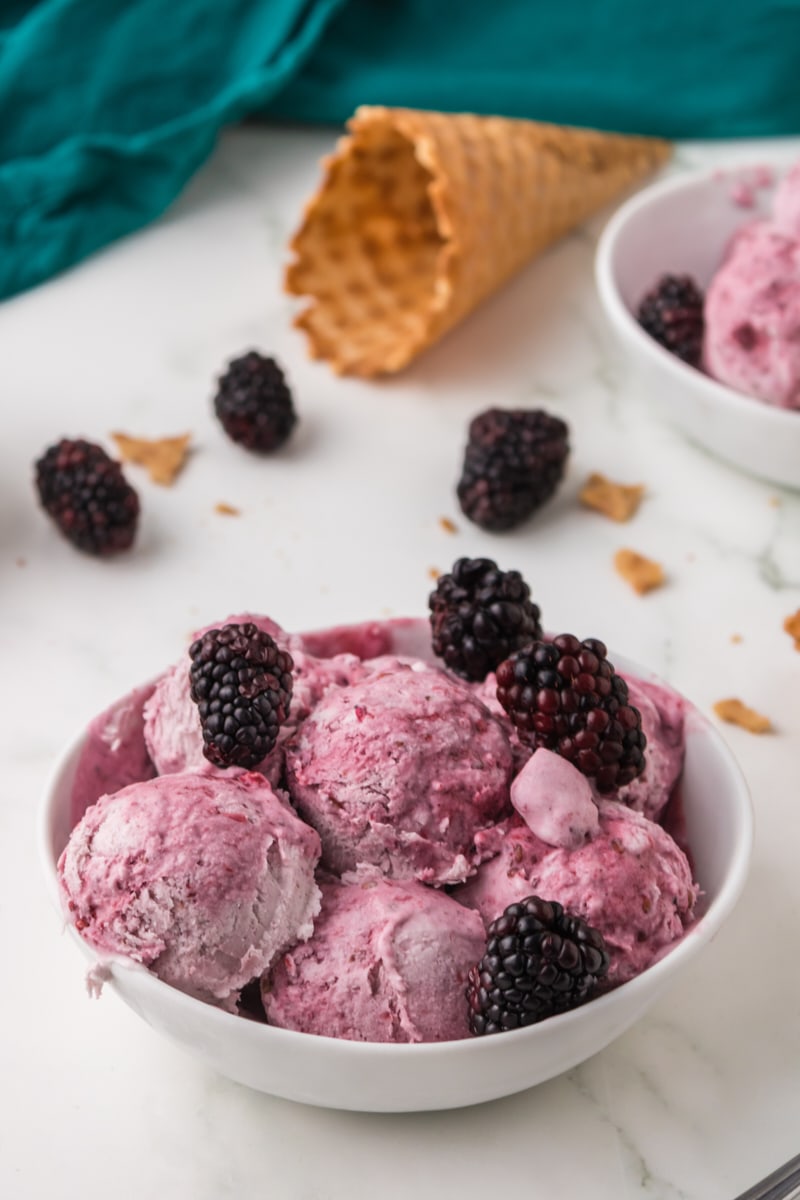 a white bowl filled with blackberry ice cream and fresh blackberries